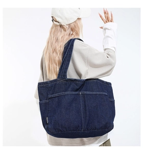 Detail of blue denim tote bag showing multiple functional pockets and durable fabric texture