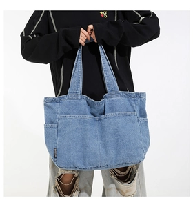 Detail of light blue denim tote bag with functional pockets and wash texture finish