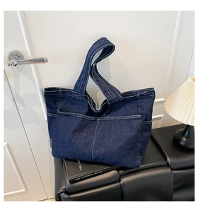 Detail of dark blue denim tote bag with white contrast stitching on a leather bench