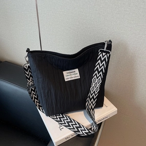 Black wrinkled fabric tote bag with geometric woven strap on a minimalist background