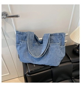 Detail view of large denim tote bag featuring side pocket and textured blue wash fabric