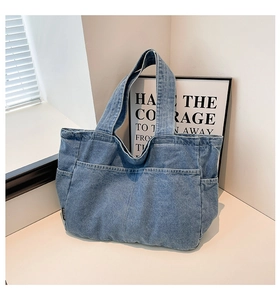 Detail of vintage denim tote bag showing large front pocket and washed fabric texture