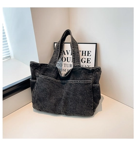 Detail of dark grey denim tote bag showing side pockets and washed fabric texture