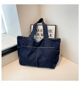 Detail of dark blue denim tote bag with white contrast stitching and dual front pockets