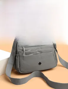 Detail view of the gray waterproof nylon bag with multiple front zipper pockets and strap
