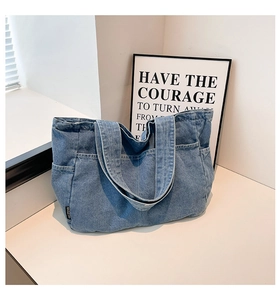 Detail of blue denim tote bag featuring external pockets and wide shoulder straps