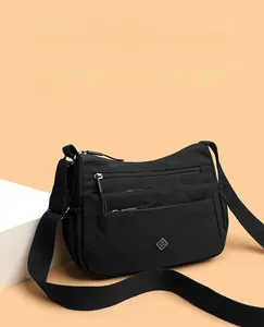 Detail of black nylon crossbody bag featuring multiple zipper pockets and wide strap