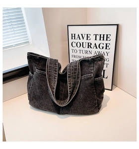 Detail of gray washed denim tote bag with side pockets on a white minimalist surface