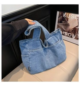 Detailed view of blue denim tote bag featuring multi-pocket design and water-washed texture