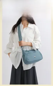 Close-up of light blue nylon crossbody bag with multiple pockets and metal detail
