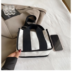 Detail der minimalistischen Canvas-Tasche mit schwarzen Kontrastgurten und Schultergurt