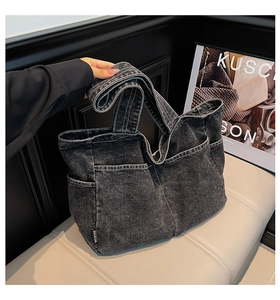 Detail of dark gray washed denim tote bag showing multiple pockets and wide handles