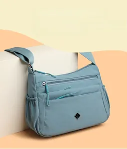 Detail of light blue nylon crossbody bag featuring multi-pocket storage and wide strap
