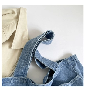 Close-up of double stitching detail and durable handle on washed blue denim tote bag