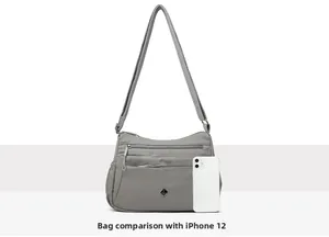 Size comparison between the grey multi-layer nylon crossbody bag and an iPhone 12