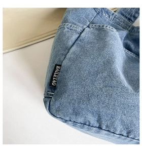 Close-up of vintage denim tote bag showing twill fabric texture and woven logo tag