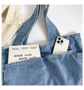 Close-up of washed blue denim tote bag featuring multiple front pockets and soft texture