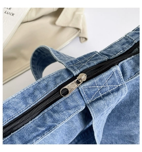 Macro detail of high-quality denim tote bag featuring silver zipper and white stitching