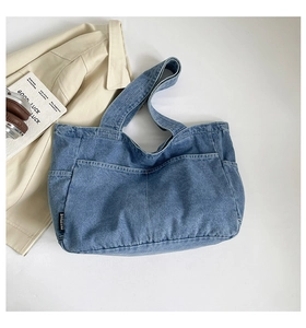 Detail of blue denim tote bag texture showing reinforced stitching and brand tag