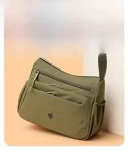 Detailed close-up of a green nylon crossbody bag with multiple pockets and fabric strap