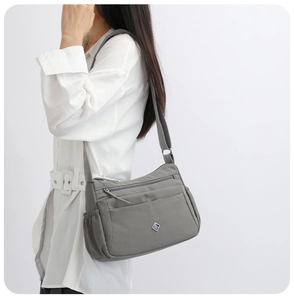 Detail of grey nylon crossbody bag with multiple zippers and adjustable strap for work
