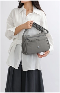 Detail view of large capacity dark grey nylon shoulder bag with multiple zippers