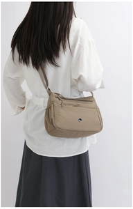 Rear view of khaki nylon crossbody bag with adjustable strap and multiple zipper pockets