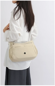 Detailed side view of beige nylon crossbody bag featuring multi-layer zip pockets