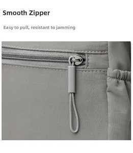 Detail of smooth zipper closure on gray nylon crossbody bag with textured fabric surface