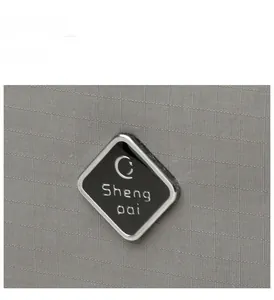 Detail of grey checkered nylon fabric with a diamond-shaped metallic logo plaque