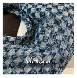 Close-up of blue and white checkered denim fabric with distressed fringe details and zipper