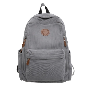 Minimalist grey corduroy backpack with front pocket and durable brown leather zipper pullers