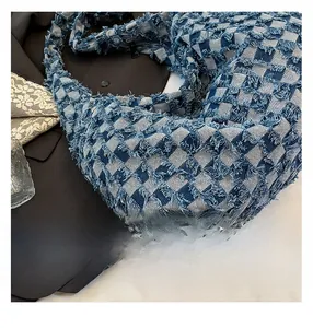 Detail view of blue plaid denim tote bag with frayed edges and secure black zipper closure