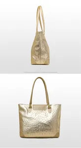 Detail of large golden tote bag featuring realistic ostrich leather texture and reinforced base