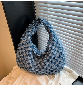 Detail of blue and white checkered denim tote bag with vintage frayed tassel edges