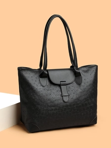 Detail view of black ostrich texture tote bag with reinforced corners and buckle straps
