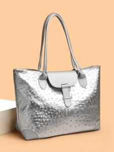 Detail view of silver embossed ostrich texture and metal buckle on large tote bag