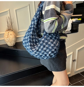 Detail of blue checkerboard denim tote bag with frayed edges and secure zipper closure