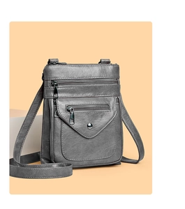 Detail view of a gray multi-layer crossbody bag with silver zippers and front buckle pocket