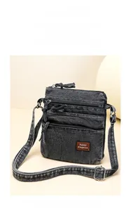 Detailed close-up of distressed denim bucket bag with triple-zipper layers and leather tag