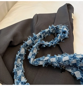Detail of blue and white checkered denim strap with frayed edges and metal zipper