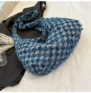 Close-up of denim crossbody bag with blue checkerboard pattern and frayed fringe details