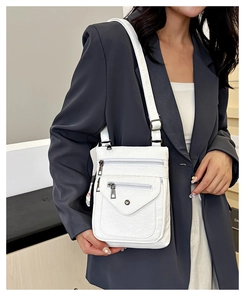 Detail view of white lychee texture PU leather crossbody bag with multi-zipper pockets
