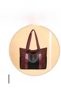 Detail of burgundy quilted nylon tote bag with black leather stitching and wide strap