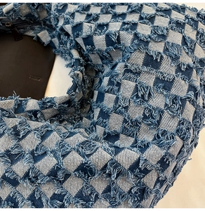 Detailed macro view of checkered denim texture with frayed fringe and metal zipper