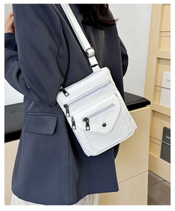 Detail of white crossbody bag with multi-zipper pockets and lychee textured faux leather