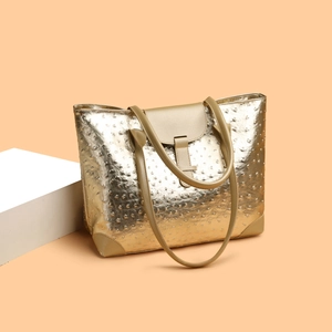 Metallic gold ostrich pattern tote bag with top handles and front buckle on neutral background