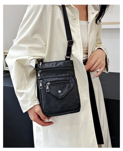 Close-up of black retro soft leather crossbody bag with multiple zipper compartments