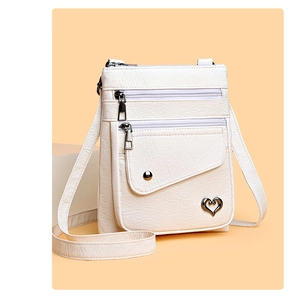 Detail of white lychee leather texture on crossbody bag with heart charm and zippers