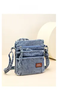 Detail of light blue denim crossbody bag with multiple zip pockets and rabbit elegance tag
